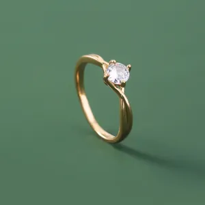 Gedetailleerde close-up van een chique vergulde getwiste ring met heldere zirkonia steen.