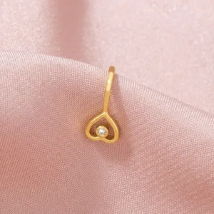 Primo piano dettagliato del delicato anello da naso dorato a forma di cuore con cristallo.