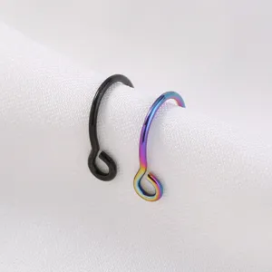 Close-up van minimalisten piercingringen met zwarte en regenboogafwerking op witte stof.