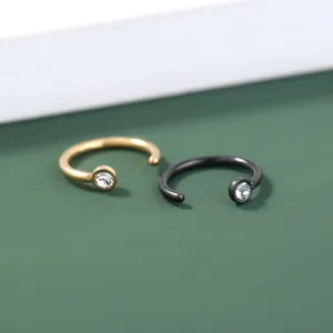 Close-up van elegante gouden en zwarte kristallen piercingringen, eenvoudig en veelzijdig.