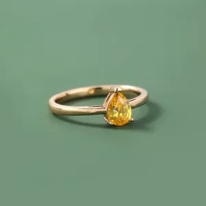 Detailopname van de elegante gouden metalen ring met briljante gele peervormige zirkoniakristal.