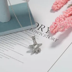 Silver starfish pendant necklace with shining rhinestones and luminous stone center detail.