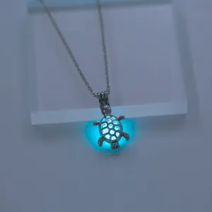 Detailaufnahme einer leuchtenden Schildkröten Halskette mit blauem Nachtleuchteffekt Anhänger.