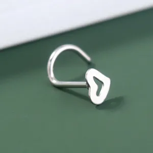 Nahaufnahme des silbernen Nasensteckers mit hohlem Herz, Körperpiercing Schmuckdetail.