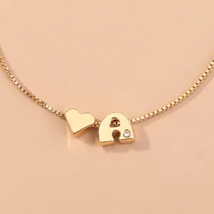 Close-up of the gold letter A and heart pendant on a delicate box chain bracelet detail.