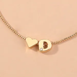 Close-up detail of gold box chain necklace featuring a cute heart and sparkling letter D charm.