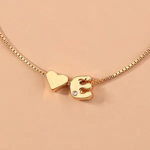 Close-up view of a minimalist gold box chain bracelet featuring a heart and letter E pendant.