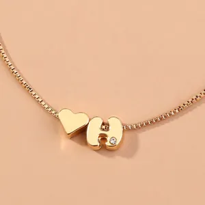 Gold initial letter H and heart charm box chain detail closeup fashion jewelry accessory.