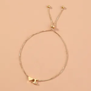 Close-up detail of golden box chain bracelet featuring slider bead, heart and letter charm.