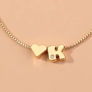 Gold tone box chain detail view featuring a heart charm and sparkling letter K pendant.