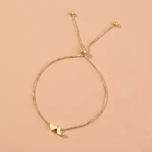 Gold box chain bracelet detail, adjustable copper bead with heart and letter charm accent.