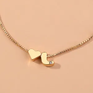Detail view of a gold-toned box chain featuring a heart and letter J charm with crystal.