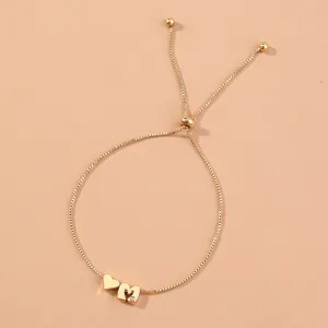 Close-up detail of gold adjustable box chain bracelet with heart and letter M charms.