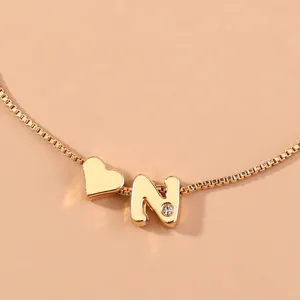 Gold-plated box chain bracelet featuring a heart charm and an alphabet N pendant with stone.