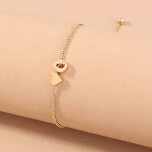Detail shot of gold box chain bracelet with letter and heart pendants, adjustable sliding bead.