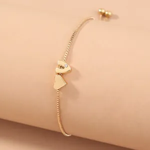 Close-up detail view of the elegant gold slider letter and heart bracelet design.