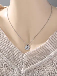 Close-up of a minimalist stainless steel letter A round pendant clavicle chain necklace.