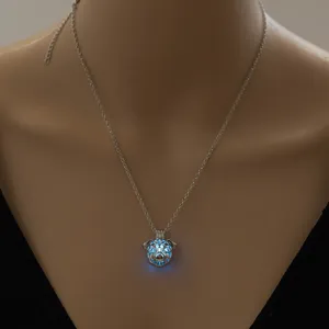 Detailed view of a silver pug dog cage pendant necklace with a glowing luminous bead.