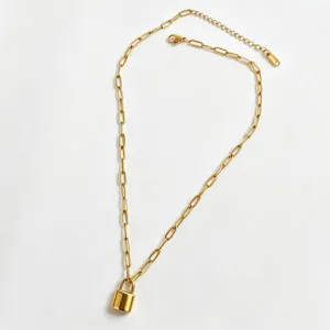 Gold padlock necklace detail showing polished mini lock pendant and paperclip chain links.