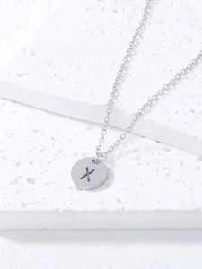 Close-up detail of a minimalist silver stainless steel necklace featuring a round letter X pendant.
