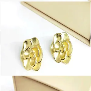 Detailed view of vintage gold metal camellia flower earrings, exquisite texture and design.
