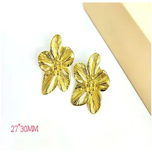 Detail close-up view of golden five-petal flower earrings featuring textured metal design.
