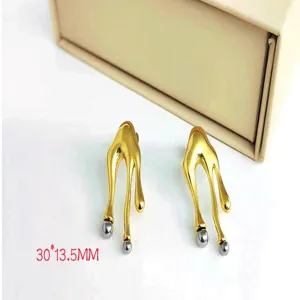 Detailed shot of irregular abstract melting metal earrings with gold and silver tone finish.