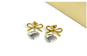 Detailed closeup of elegant French style bow and heart stainless steel dangle earrings.