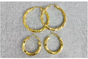 Close-up view of twisted gold hoop earrings showing detailed texture and modern design.