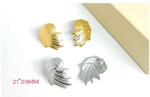 Detail view of stylish metal spiral wing earrings in gold and silver, modern statement jewelry.
