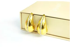 Detailed close-up of gold teardrop hoop earrings featuring a sparkling row of clear rhinestones.