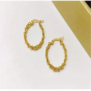 Gold braided twisted hoop earrings detail shot, elegant everyday jewelry accessory style.
