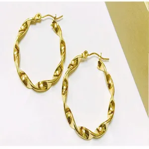 Close up detail of golden twisted hoop earrings stainless steel metal jewelry design.