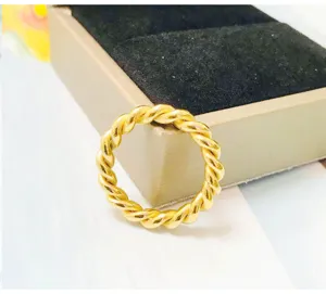 Close-up view of a stylish gold twisted stainless steel ring, sleek texture and trendy design.