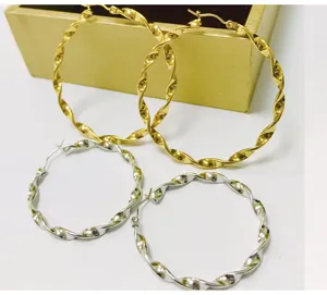 Close-up of twisted hoop earrings in gold and silver finish, showcasing textured detail.