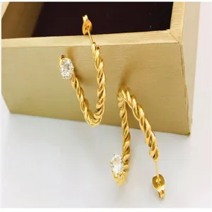 Detail shot of 18k gold plated twisted rope hoop earrings sparkling with a clear zircon stone.