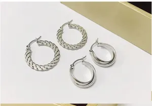 Detail view of silver metal hoop earrings featuring twisted rope and double-layered smooth designs.