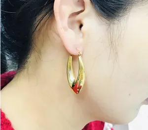 Close-up detail shot of shiny gold stainless steel V-shaped geometric hoop earrings.