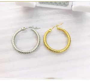 Detailed shot of snake skin textured hoop earrings in gold and silver, showing intricate pattern.