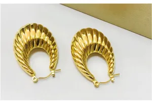 Detailed shot of ribbed gold U-shaped hoop earrings, highlighting fine texture.