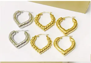 Close-up detail of trendy heart-shaped bamboo texture hoop earrings in silver and gold finishes.