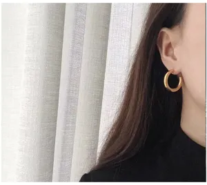 Detailed shot of thick gold C-shaped hoop earrings worn on ear, chic minimalist style.