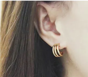 Detail shot of French triple-loop stainless steel 18k gold hoop earrings worn on ear.