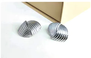 Detailed shot of silver metallic ribbed twisted stud earrings with glossy finish.