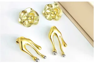 Detailed view of gold camellia flower earrings and abstract fluid metal earrings set.