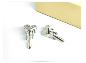 Close-up detail of silver lava heart earrings, unique melting metal fashion jewelry.