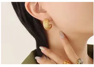 Detailed shot of textured gold C-shaped hoop earrings, offering a chic French minimalist style.