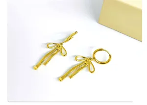 Detail shot of gold-plated stainless steel bow earrings, elegant minimalist jewelry design.