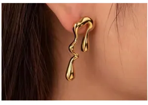 Close up detail of irregular liquid metal gold stud earrings modern artistic jewelry design