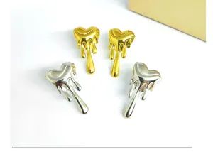 Detailed view of metal molten heart earrings showing polished gold and silver finishes.